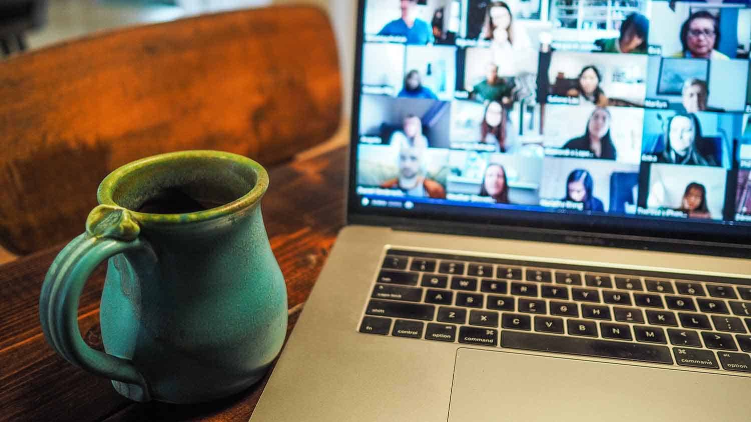 A cup of tea next to a laptop showing a webinar