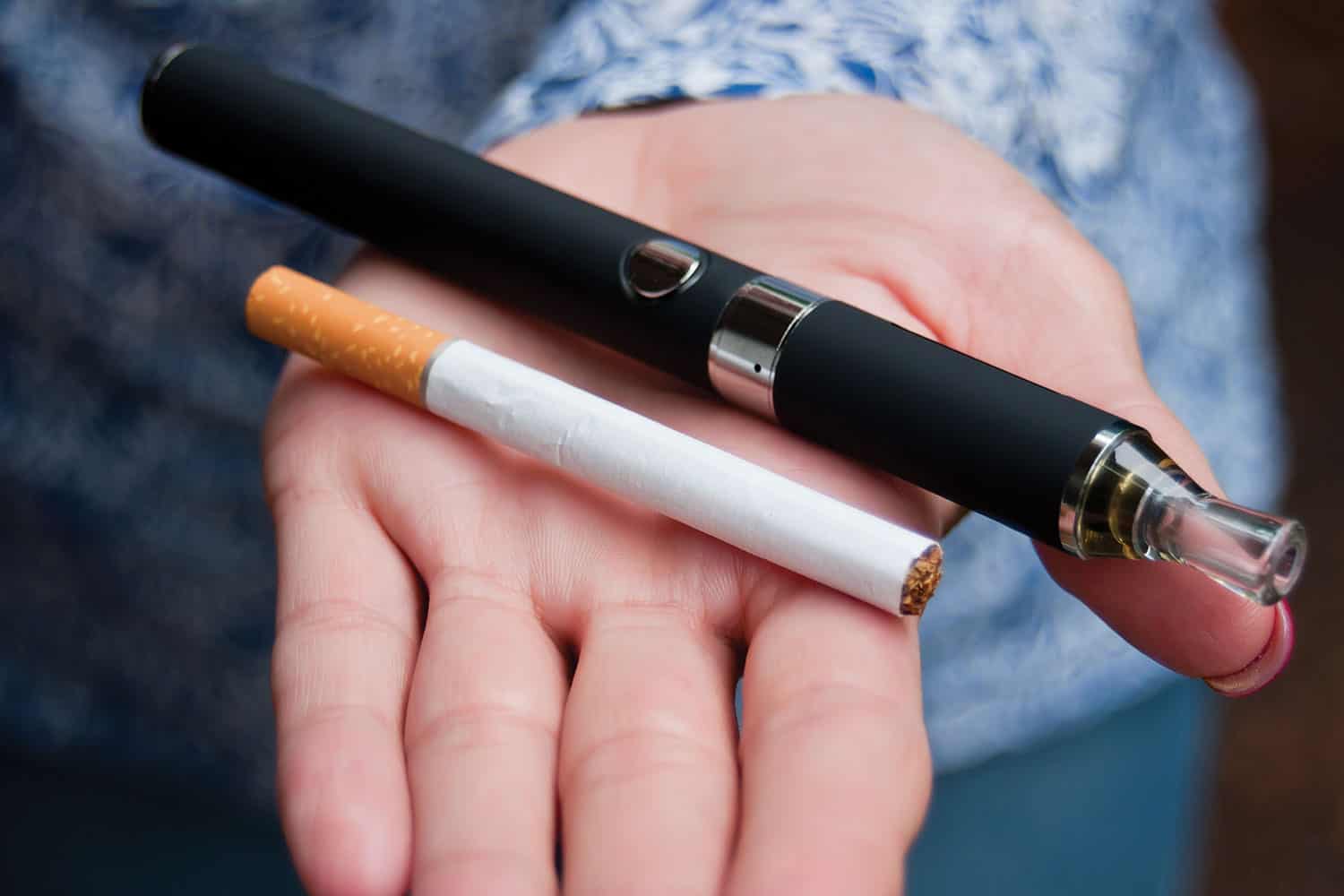 Open hand holding cigarette and vape.