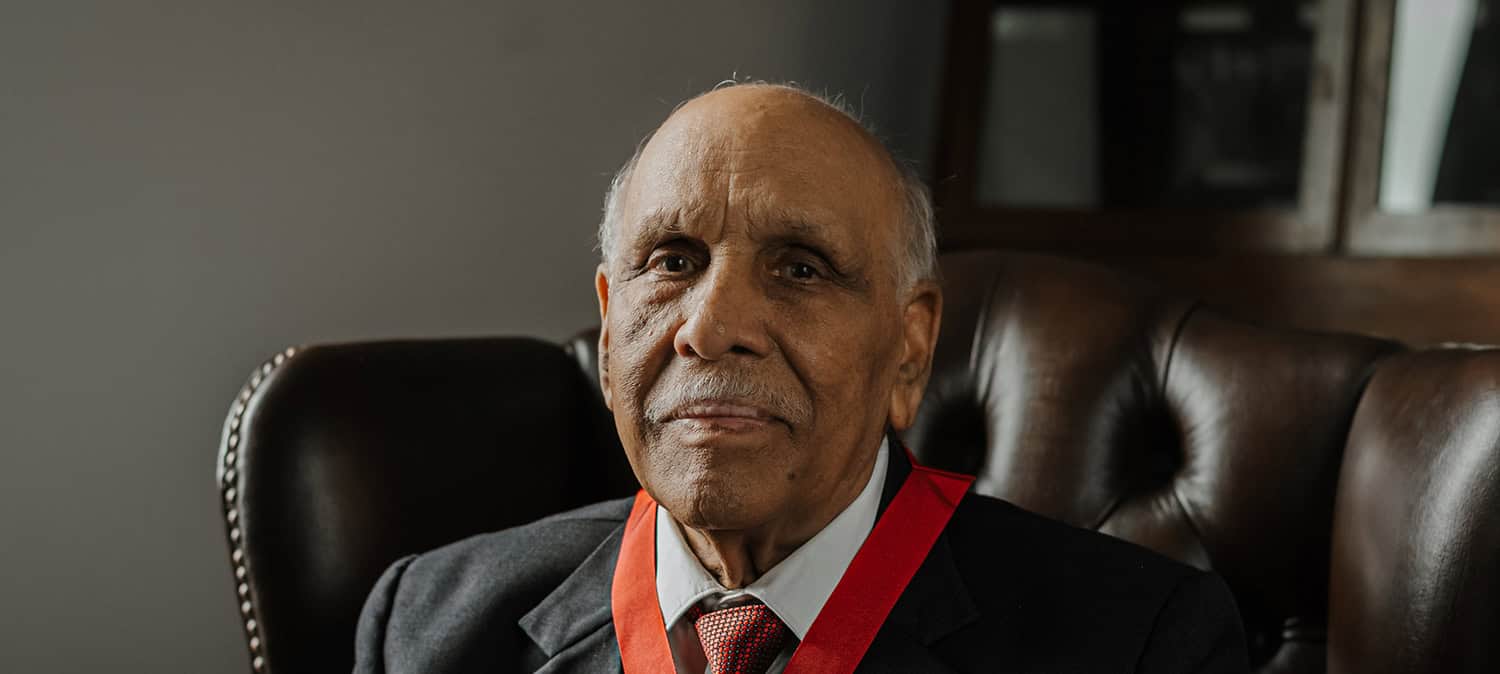 photo portrait of Cllr Jagdish Sharma, looking left, in ceremonial red and black robes; black and white photo of Cllr Sharma with Queen Elizabeth The Queen Mother