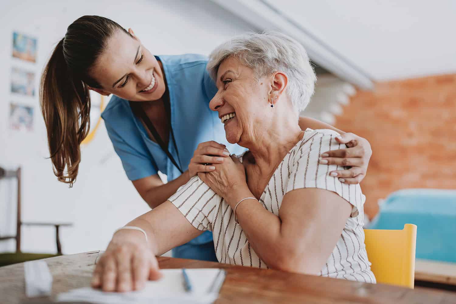 smiling female care worker with older woman sitting down