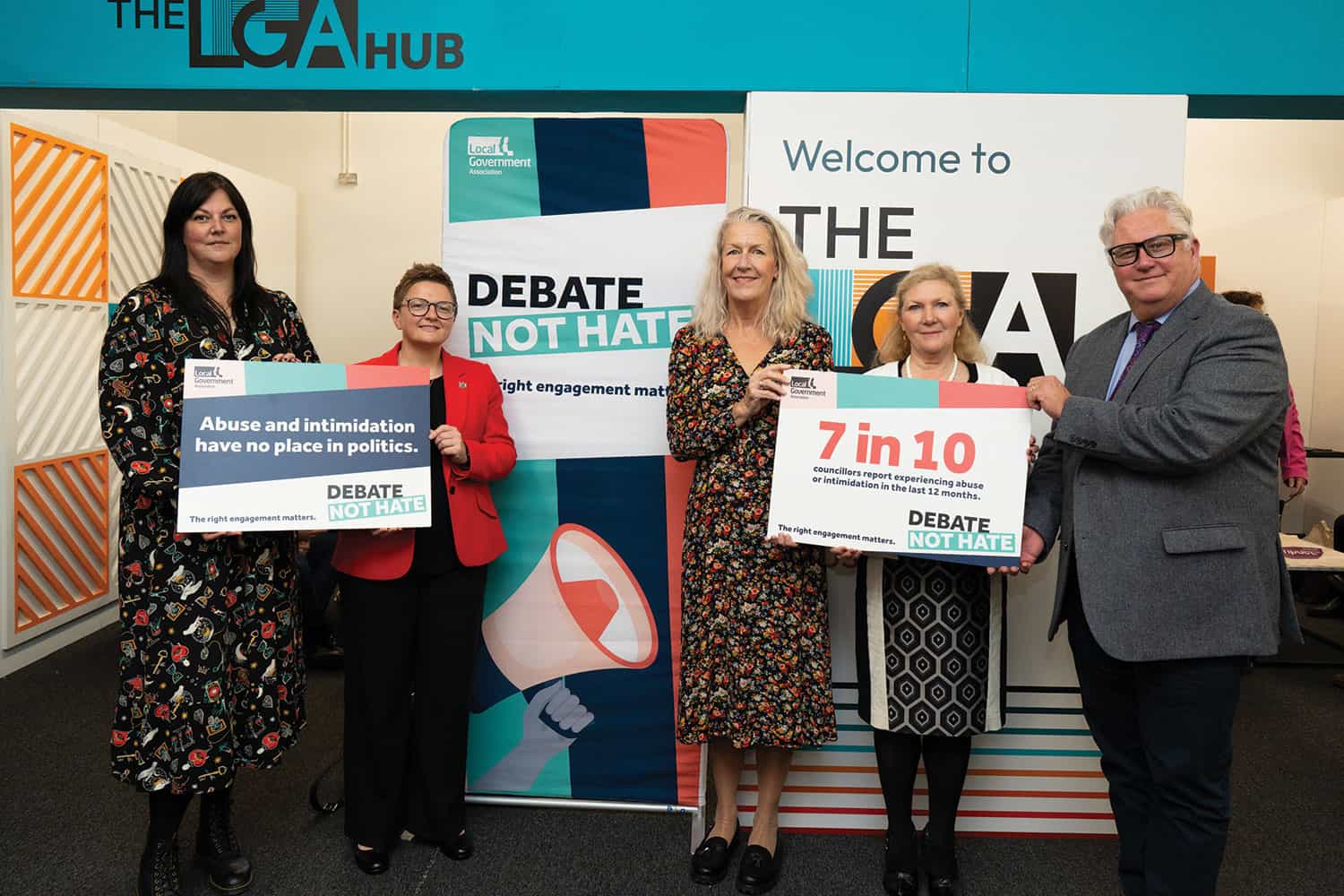 photo of LGA chair, group leaders and group representatives holding and standing in front of ‘Debate Not Hate’ placards and the LGA’s conference hub