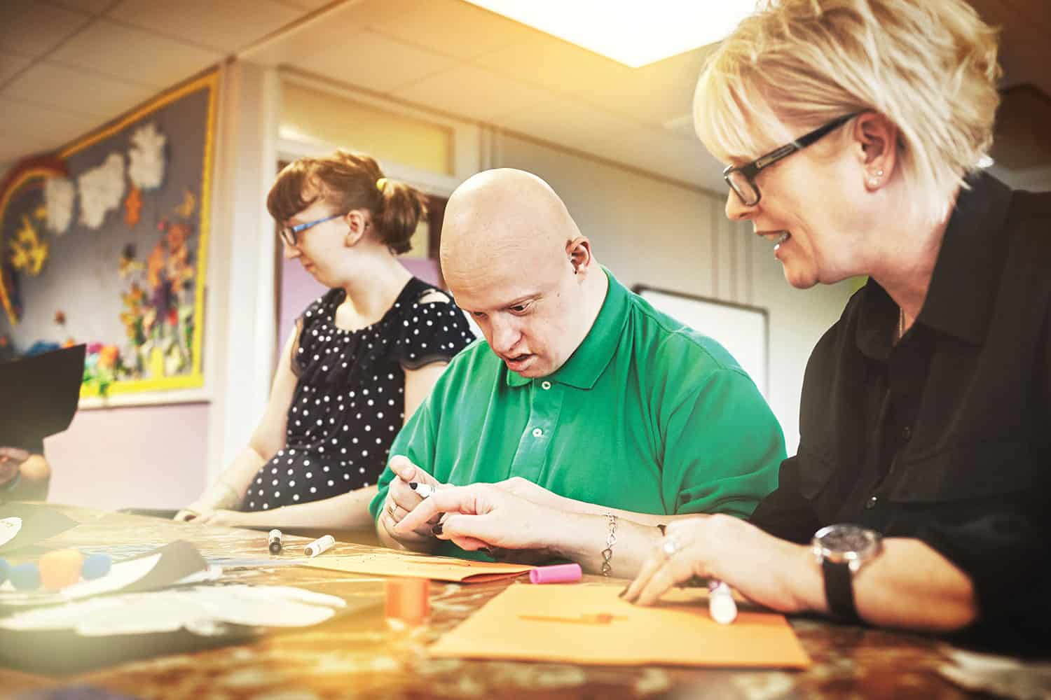 photo of a man with learning disabilities crafting with care workers