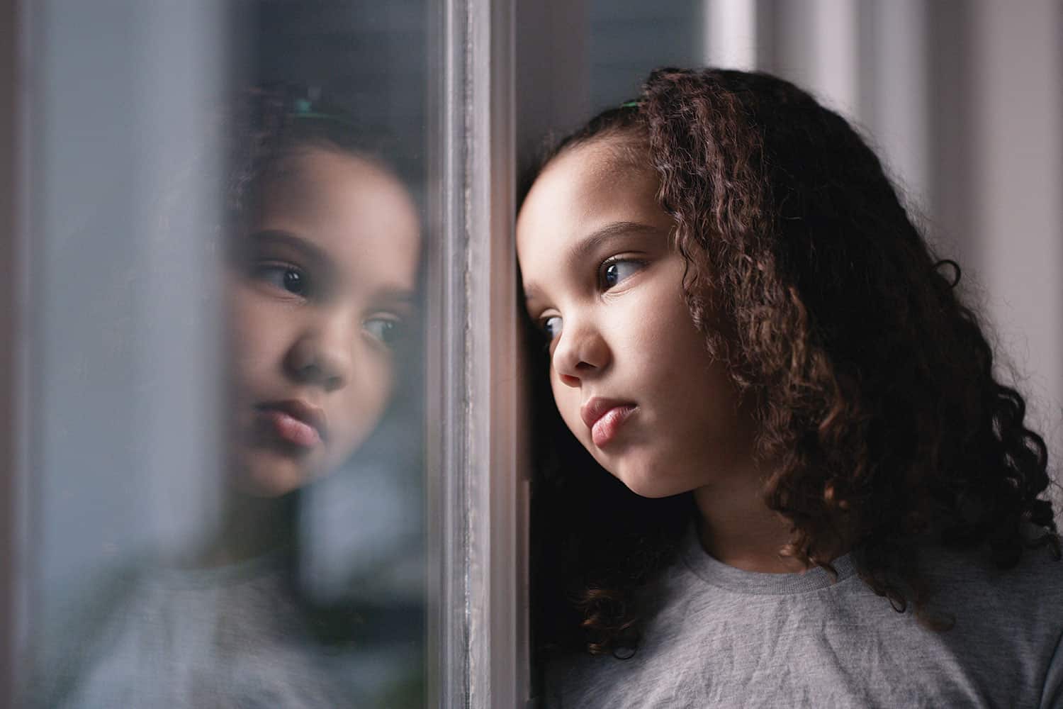 photo close-up of young girl looking sadly through window