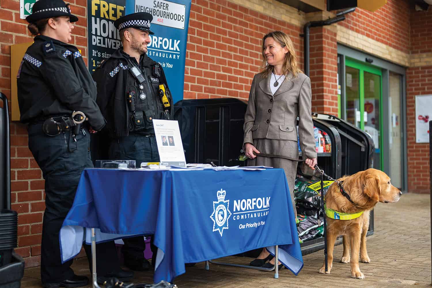 Cllr Lana Hempsall (Con), of Broadland District Council and Norfolk County Council, with her guide dog, speaking with police officers at a community stand