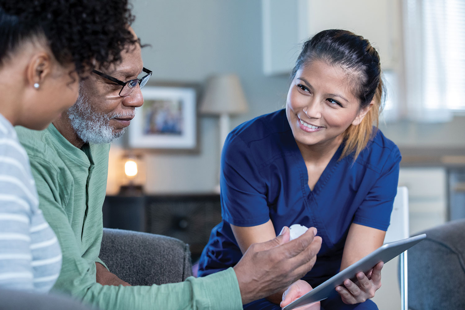 female care worker holding tablet and discussing care plans with older male