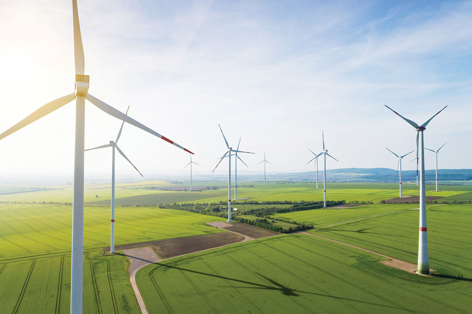 photo of onshore wind farm in green farmland with hills rising in the far background