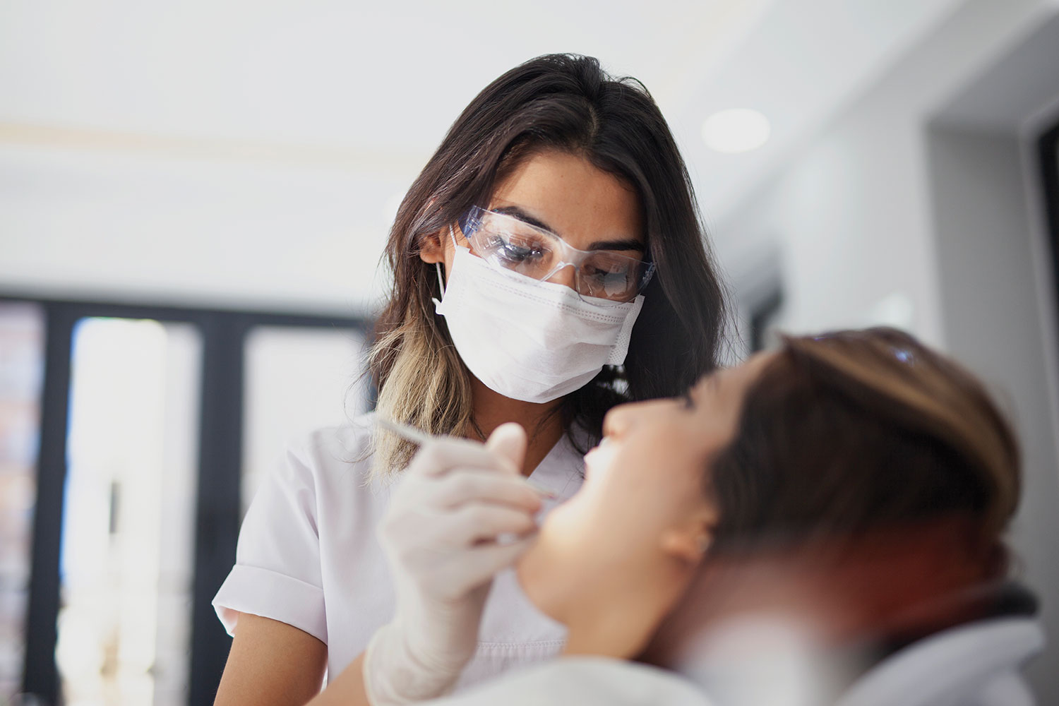 photo of female dentist examining young woman’s teeth