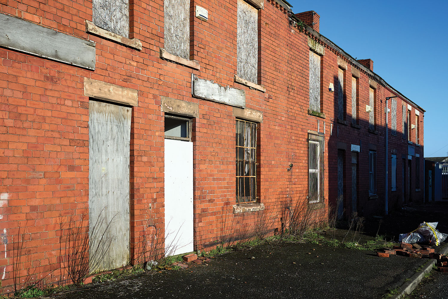 photo of red brick terrace house with boarded up windows and doors
