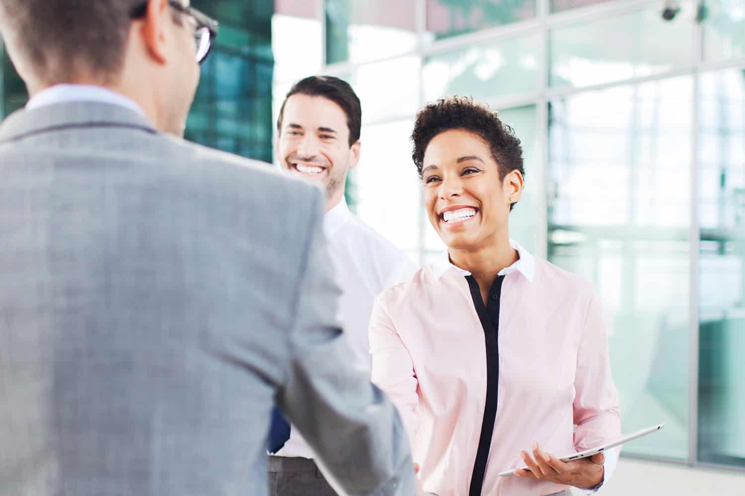 photo from behind suited man, shaking hands with younger woman in business setting